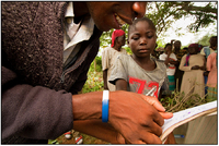 A young Kenyan boy makes a thumb print on the log sheet before receiving cassava seed from GLCI.