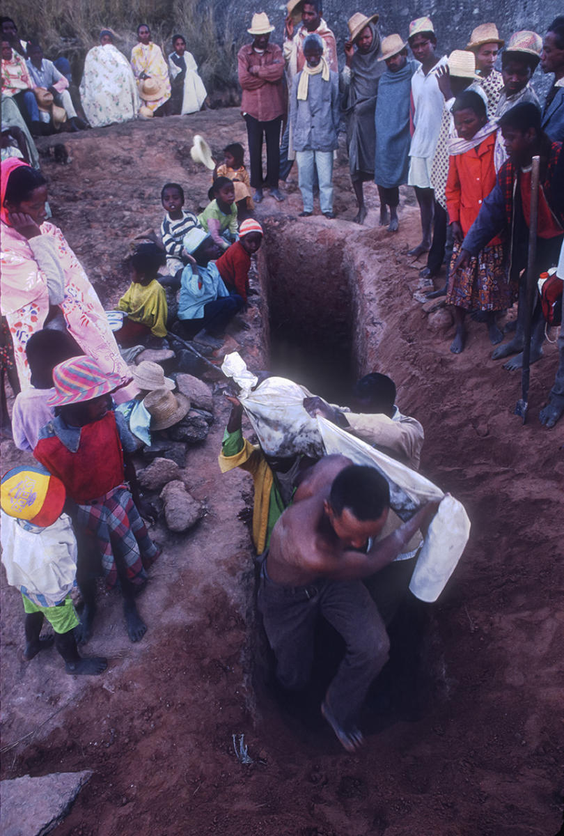 Betsileo villagers carry the remains from the tomb entrance during a Famadihana ritual, which includes exhumation and rewrapping of remains in fresh shrouds. Some Malagasy worship the ancestors, believing all will be well in their lives if they honor and remember the ancestors.