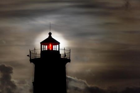 The Harvest Moon rises behind the beacon of Nubble Light in Cape Neddick, Maine. 