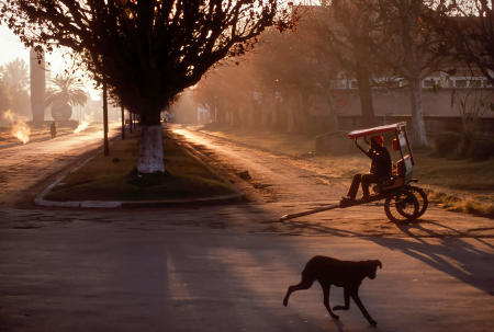 A rickshaw operator, known as "Pousse-pousse" in Madagascar, waits for customers at sunrise in Antsirabe, Madagascar.