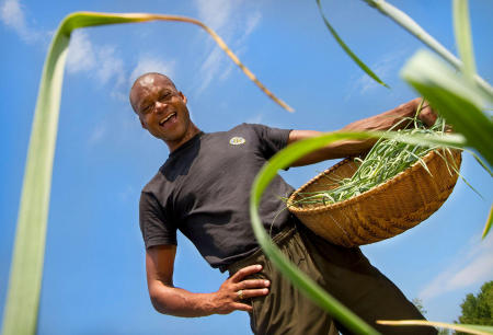 Maine legislator, farmer and fierce advocate for Maine's sustainability movement, Craig Hickman smiles while picking garlic scapes on his Annabessacook Farm in Winthrop. Shot for The Portland Press Herald.