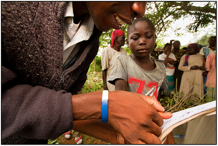 A young Kenyan boy makes a thumb print on the log sheet before receiving cassava seed from GLCI.