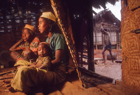 A Tanala family sits by the fire, as wood is cut outside, in remote village of Namahoaka in Madagascar.