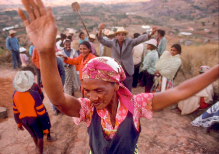 The mother of the deceased dances during Famadihana ritual, which includes exhumation and rewrapping of remains in fresh shrouds. Some Malagasy worship the ancestors, believing all will be well in their lives if they honor and remember them.