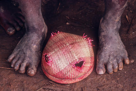 A mourner places his hat between his feet in respect, as the body is brought to the tomb during a funeral.