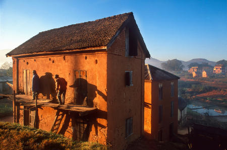 Betsileo villagers on Madagascar's High Plateau, stand on the second story deck of their mud brick home.