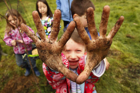 A student from the William H. Rowe School in Yarmouth shows off her dirty hands after planting apple trees during Arbor Day activities at the Spear Farm Estuary Preserve.